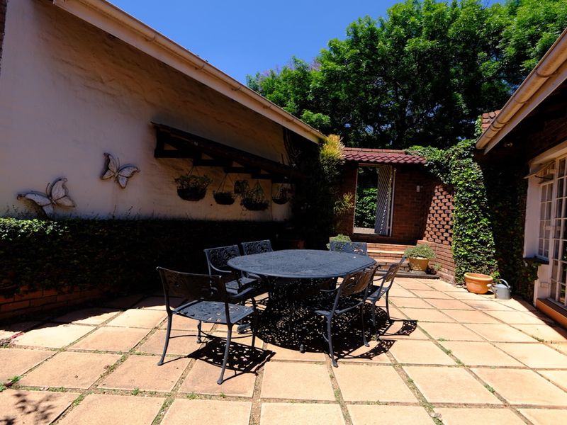 A paved outdoor patio area featuring brick walls and access to the home via french doors, offering a private space for outdoor dining.