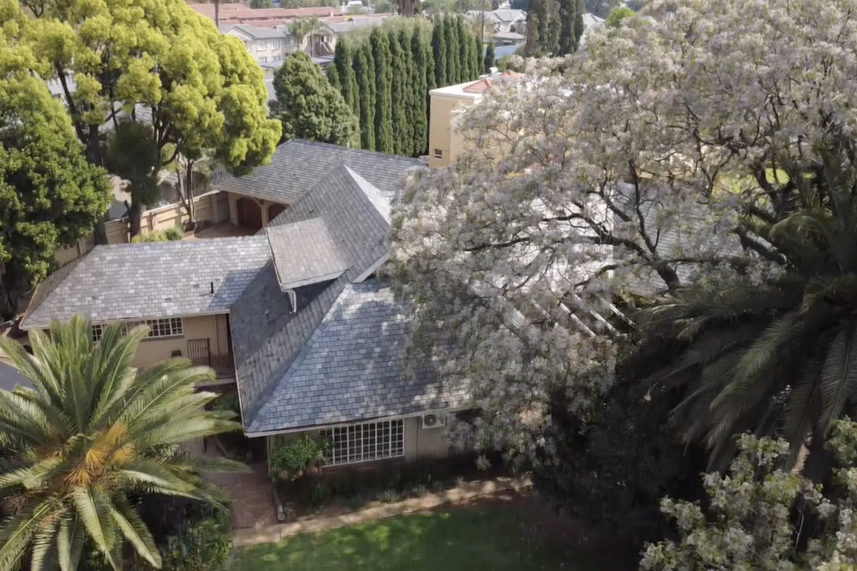 Aerial view of the property showcasing the slate roof, established garden, and surrounding mature trees.