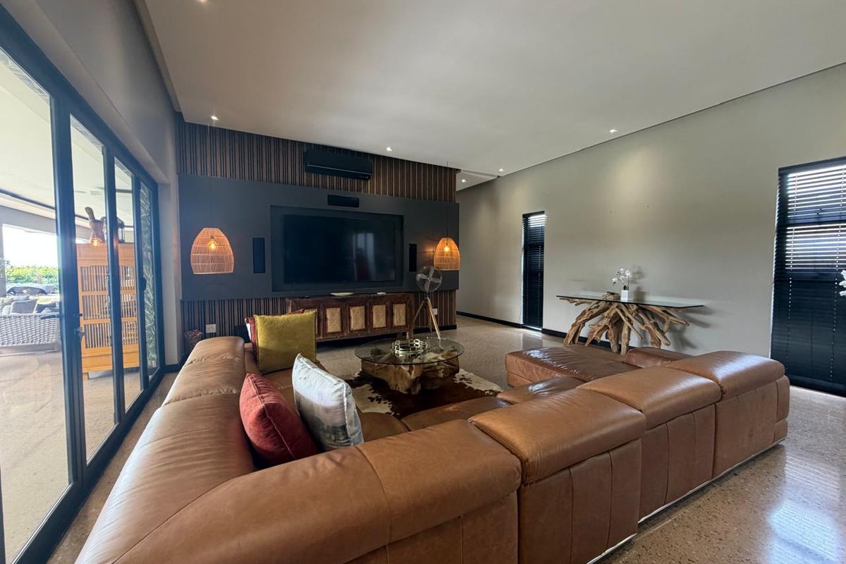 Spacious modern living room featuring polished concrete floors, a striking slatted timber feature wall, and large sliding doors providing seamless indoor-outdoor flow.