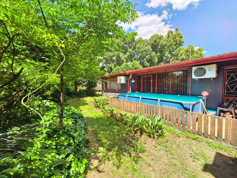 Rear garden area featuring an above-ground swimming pool, timber fencing, and exterior wall-mounted air conditioning units.