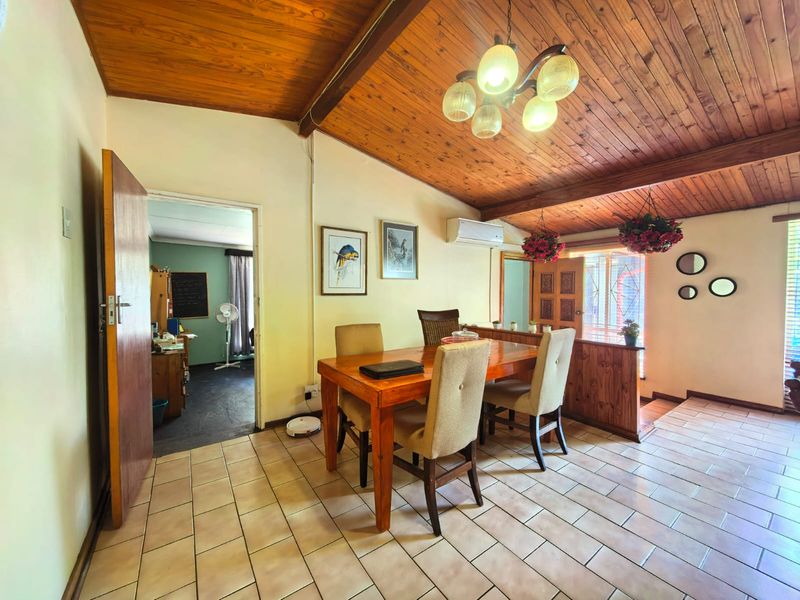 Dining area featuring a vaulted timber-clad ceiling with exposed beams, ceramic tiled flooring, and a split-system air conditioner.