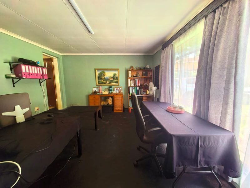 A functional office space featuring a large window for natural light and basic overhead lighting, suitable for a home workspace.