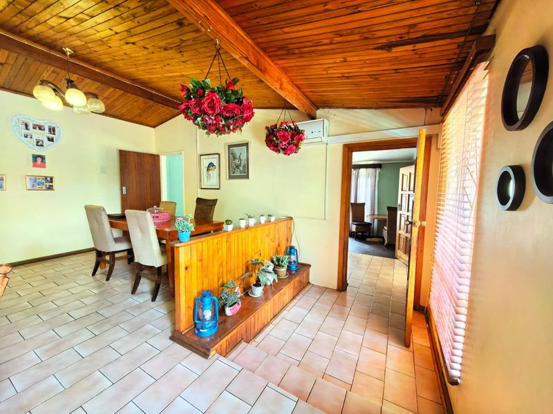 Dining area featuring a vaulted timber-clad ceiling with exposed beams, ceramic tiled flooring, and a built-in timber room divider.