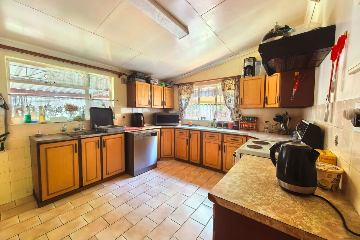 A functional kitchen featuring wooden cabinetry, tiled flooring, and a tiled backsplash, offering a dated aesthetic with potential for modern renovation.