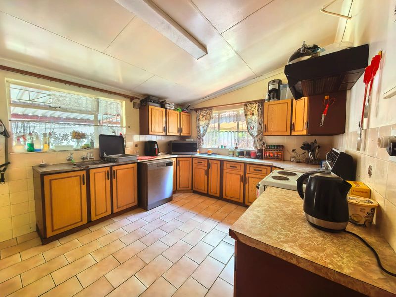 A functional kitchen featuring wooden cabinetry, tiled flooring, and a tiled backsplash, offering a dated aesthetic with potential for modern renovation.