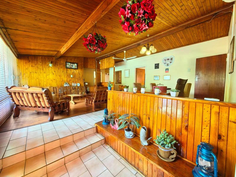 Spacious open-plan living and dining area featuring warm timber-clad vaulted ceilings, wood paneling, and a split-level layout with tiled flooring.