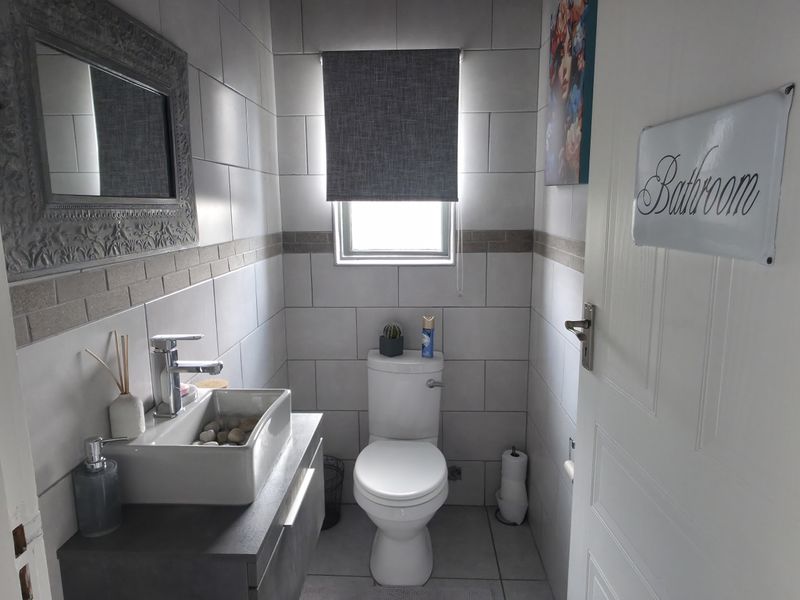 A compact, modern bathroom featuring a wall-mounted vanity with a vessel sink, tiled walls, and a clean, functional layout.