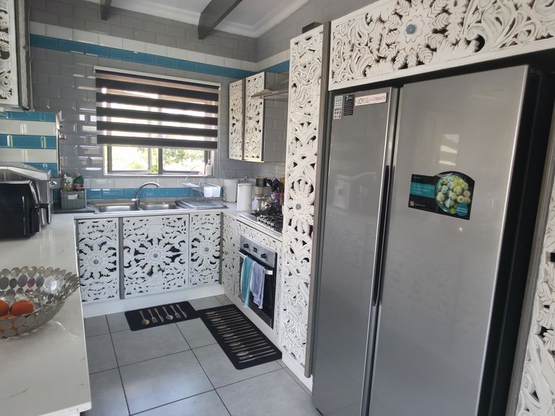 A functional kitchen featuring custom carved cabinetry, subway tile backsplash, stainless steel appliances, and tiled flooring with ample counter space.