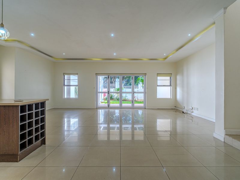Spacious open-plan living area featuring polished porcelain tiles, recessed ceiling lighting, and large sliding doors providing direct access to the rear garden.