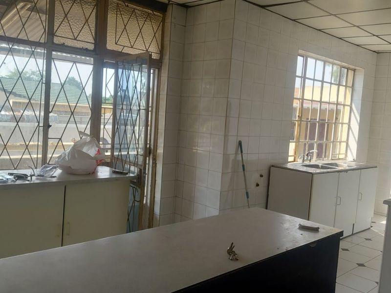 A dated kitchen featuring tiled walls, built-in cabinetry, and a double sink, offering a blank canvas for renovation and modernization.