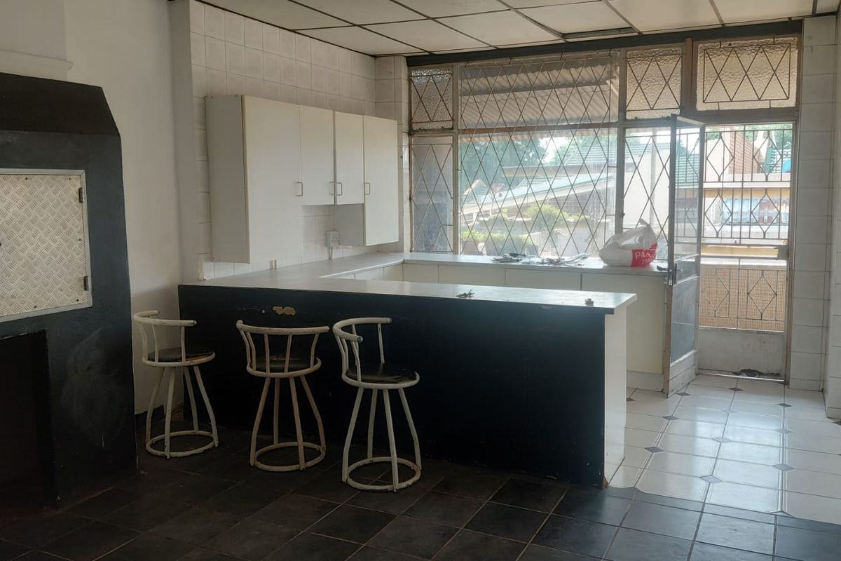 A dated kitchen area featuring built-in cabinetry, a breakfast bar, and tiled finishes, offering potential for modernization and renovation.