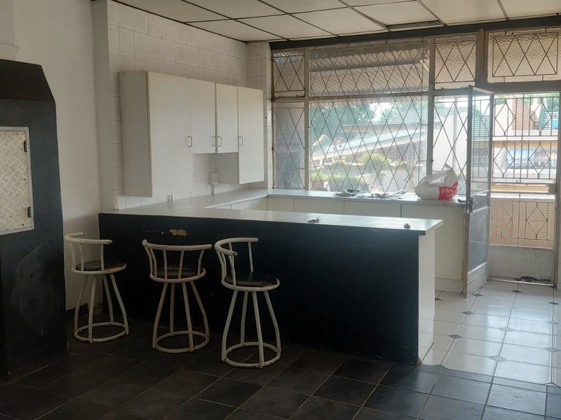 A dated kitchen area featuring built-in cabinetry, a breakfast bar, and tiled finishes, offering potential for modernization and renovation.