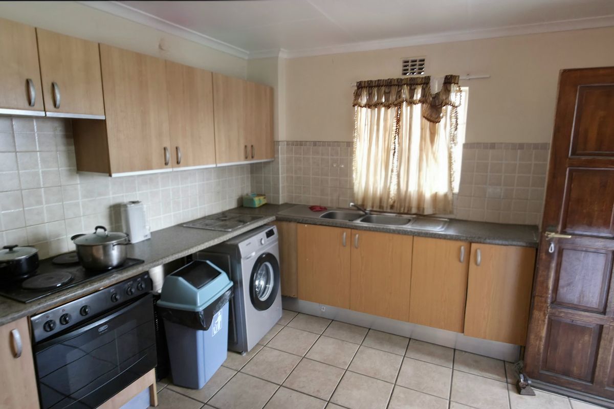 Functional kitchen featuring laminate cabinetry, built-in oven, electric hob, and double bowl sink with tiled splashback and ceramic flooring.