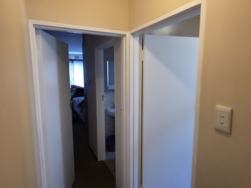 A view of a residential hallway connecting multiple rooms with standard internal doors and a light switch.