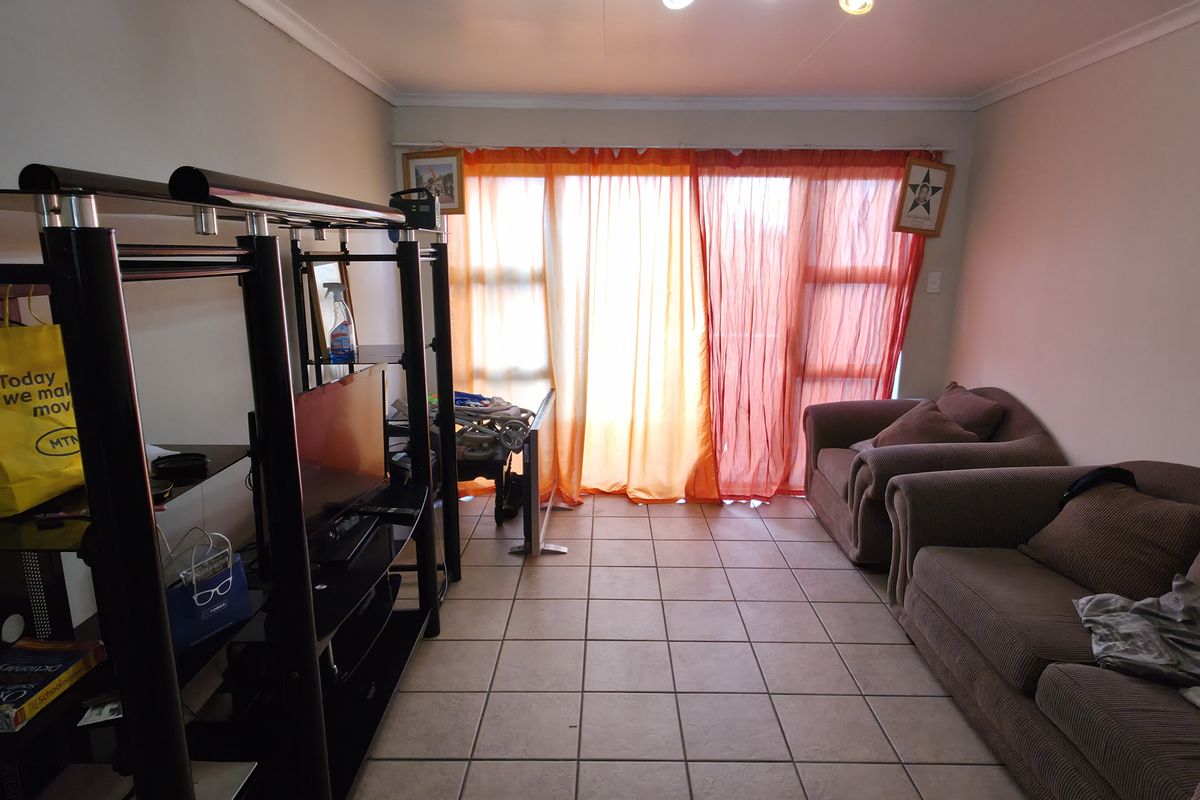 A living room featuring tiled flooring and a large sliding glass door that provides natural light.