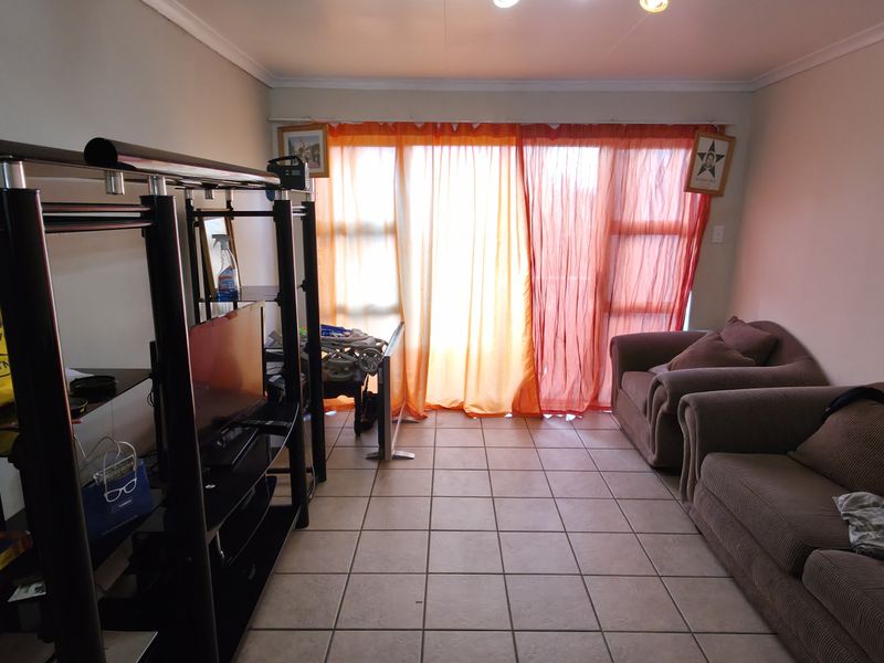 A living room featuring tiled flooring and a large sliding glass door that provides natural light.
