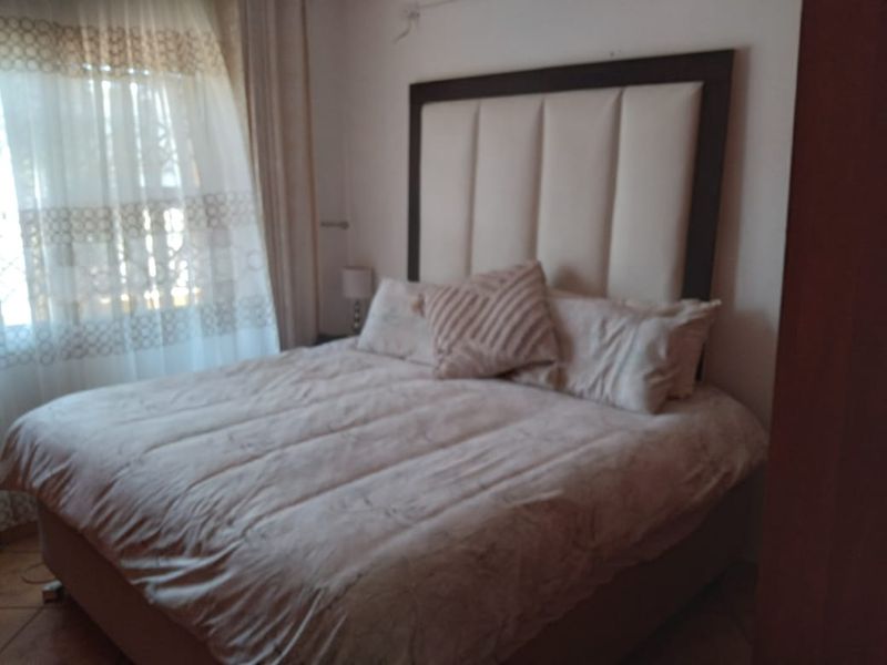 A bedroom featuring tiled flooring and window treatments, providing a functional space for rest.