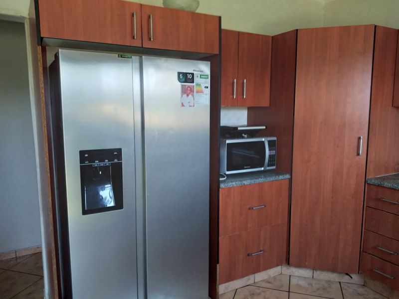 A functional kitchen area featuring wood-finish cabinetry, laminate countertops, and tiled flooring, providing ample storage space.