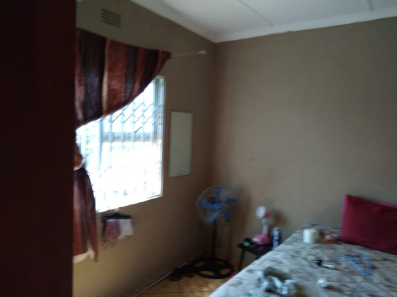 A bedroom featuring tiled flooring, security bars on the window, and neutral wall finishes.