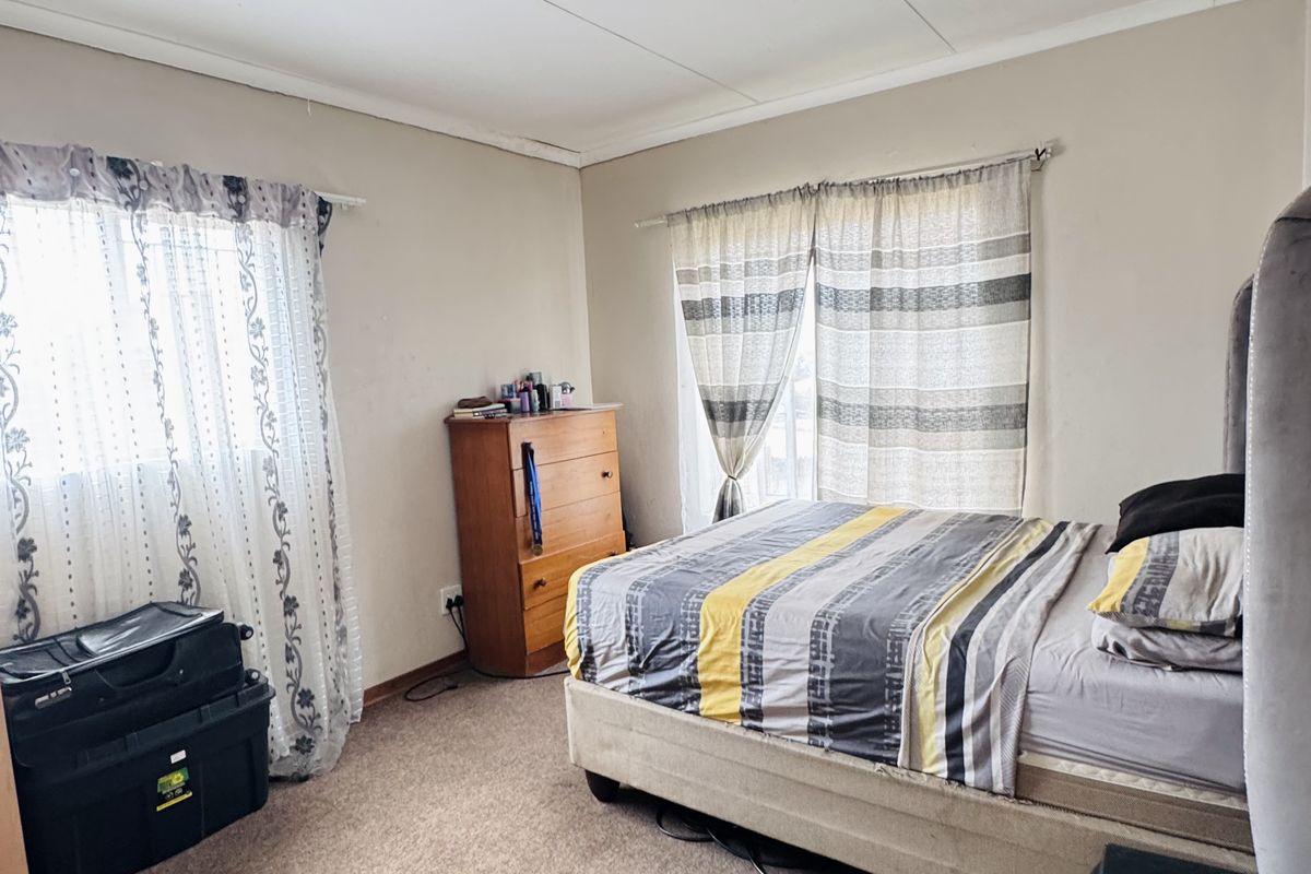A bedroom featuring carpeted flooring and a tiled ceiling. The space requires cosmetic updates to improve its overall condition and appeal.