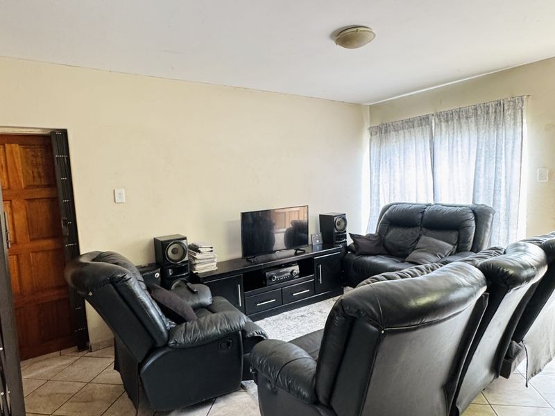 A living room featuring tiled flooring and a wooden door, offering a functional space with neutral wall tones.