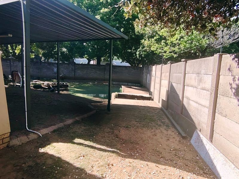 A covered outdoor patio area featuring a paved floor and enclosed by a precast concrete boundary wall, offering potential for landscaping and outdoor living.