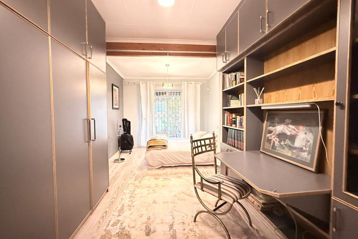 A bedroom featuring extensive built-in cabinetry, a dedicated desk area with integrated shelving, and an exposed wooden ceiling beam.