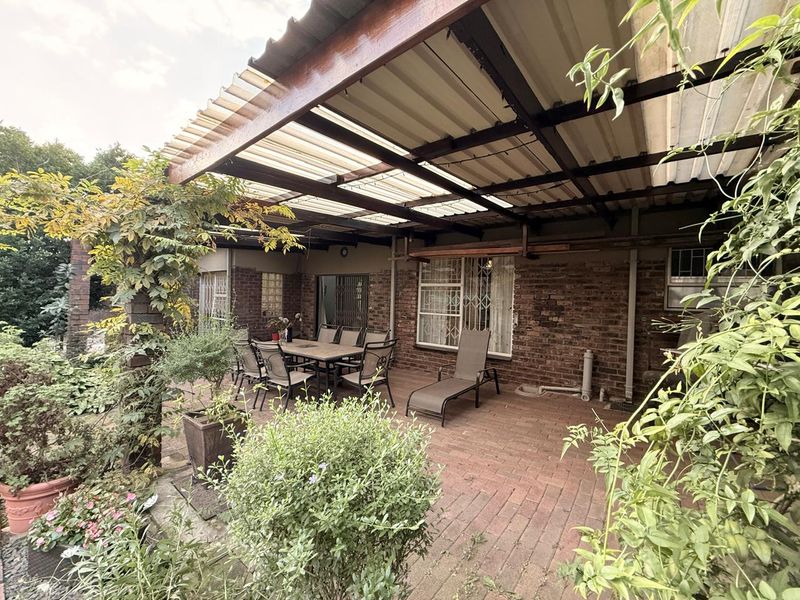 A covered outdoor patio area featuring brick paving and exposed brick walls, providing a functional space for outdoor relaxation and entertainment.