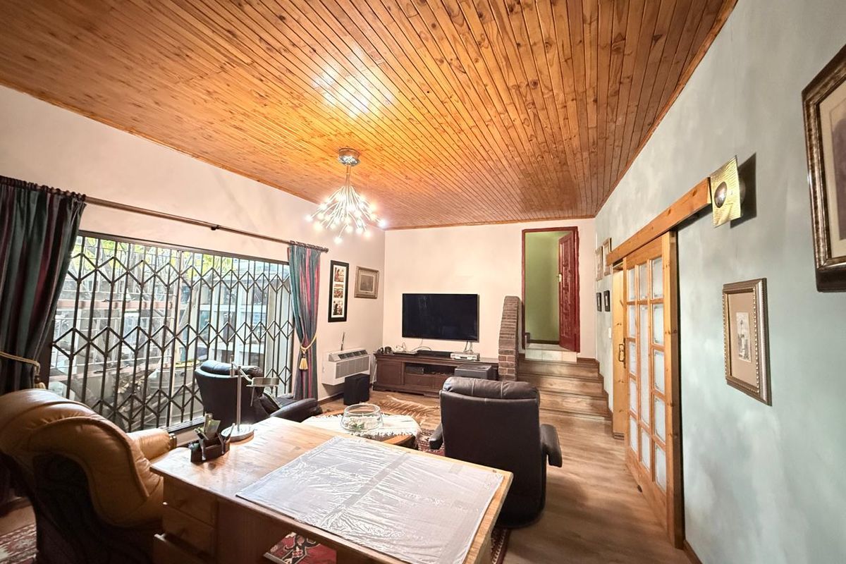 Spacious living room featuring a warm timber tongue and groove ceiling, laminate flooring, and a sliding barn door leading to adjacent areas.