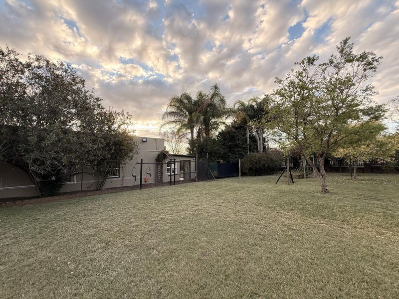 A spacious rear garden featuring a well-maintained lawn, mature trees, and perimeter fencing, providing a private outdoor area for the property.