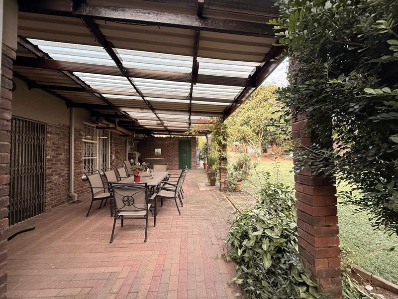 A covered outdoor patio featuring brick paving, exposed brick walls, and a translucent roof, providing a functional space for outdoor dining and relaxation.