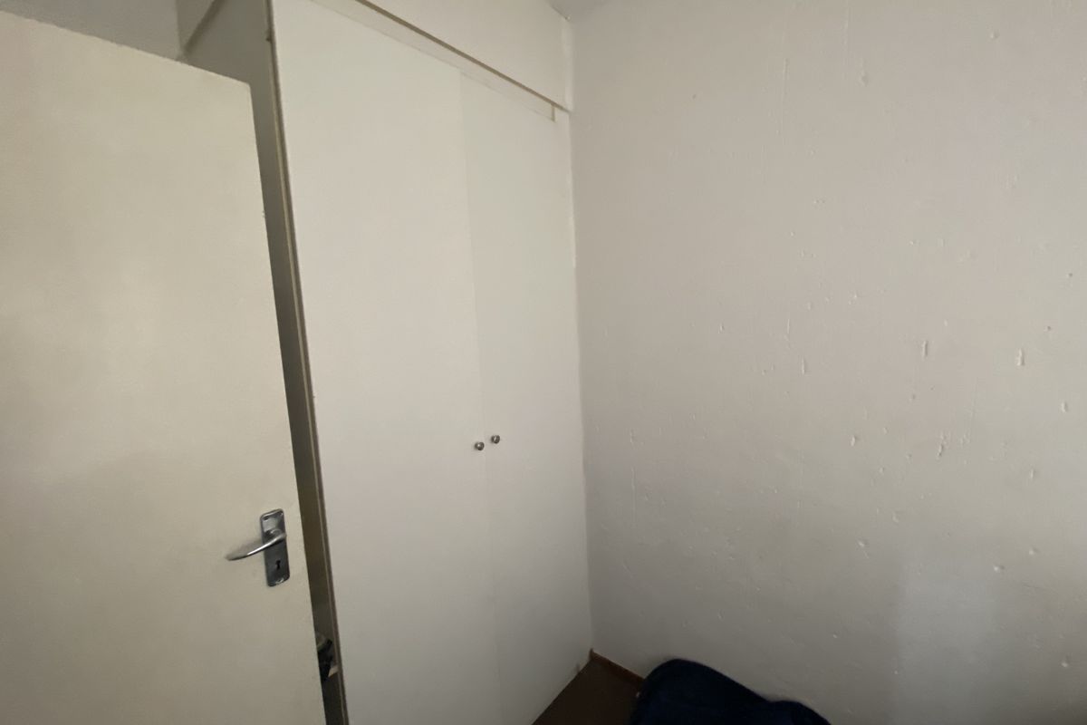 A small bedroom featuring a built-in wardrobe and plain white walls, offering a blank canvas for potential interior updates.