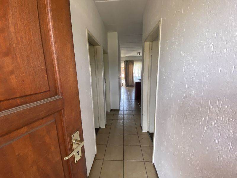 A functional hallway featuring tiled flooring and a solid timber entrance door, providing access to the interior living spaces of the townhouse.