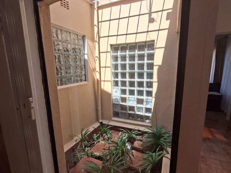 An internal courtyard or light well featuring glass block windows, metal security grille, and tiled flooring, providing natural light to the surrounding interior spaces.