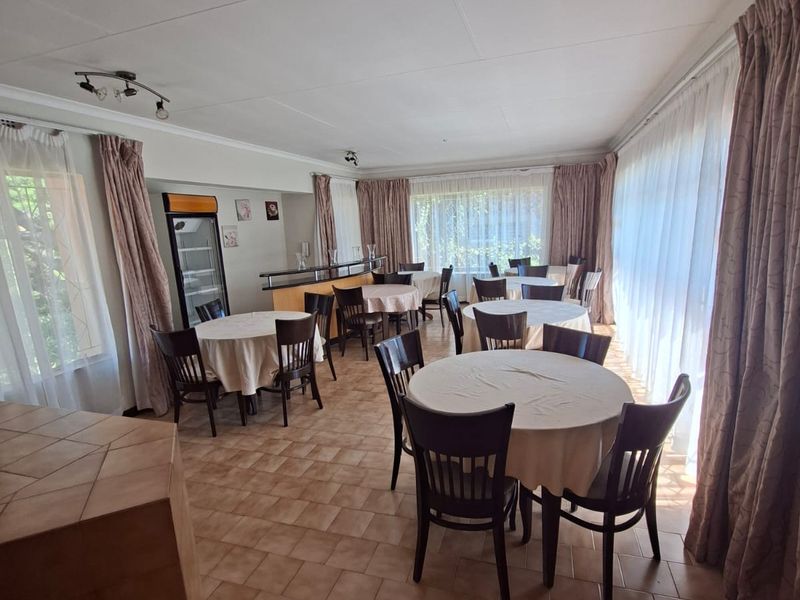 Spacious dining area featuring tiled flooring, a built-in bar counter, and ample natural light through large windows with curtain treatments.