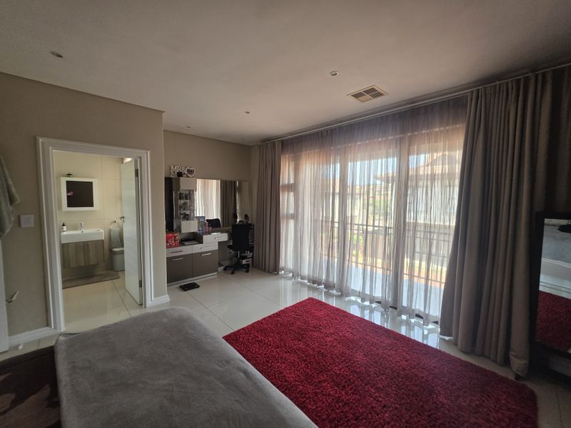 Spacious bedroom featuring tiled flooring, recessed lighting, and large sliding glass doors leading to a private balcony, with an adjoining en-suite bathroom.