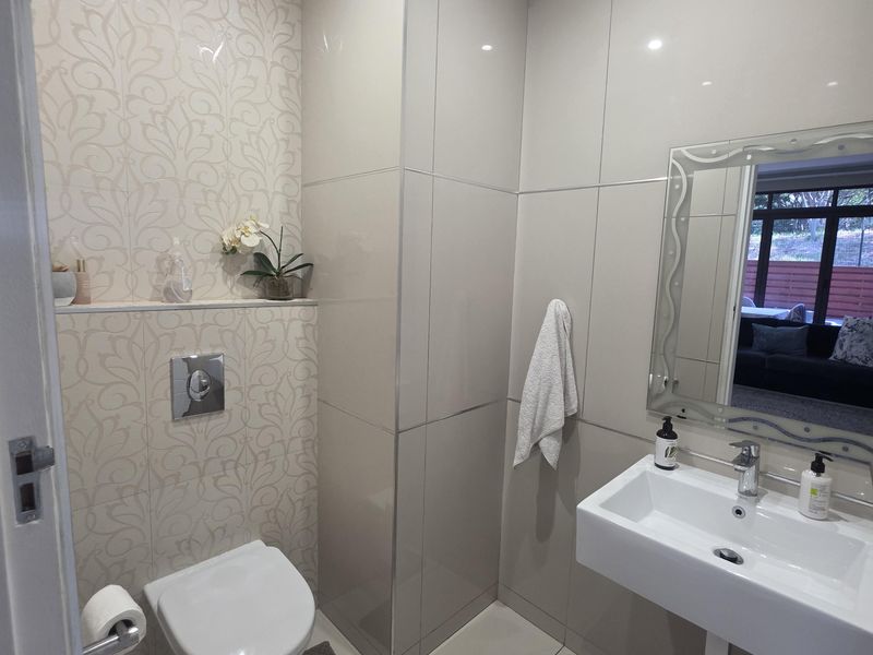 Modern guest bathroom featuring a wall-mounted toilet with concealed cistern, sleek wall-mounted basin, and elegant decorative tiling.