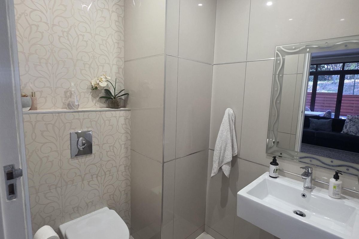 Modern guest bathroom featuring a wall-mounted toilet with concealed cistern, sleek wall-mounted basin, and elegant decorative tiling.