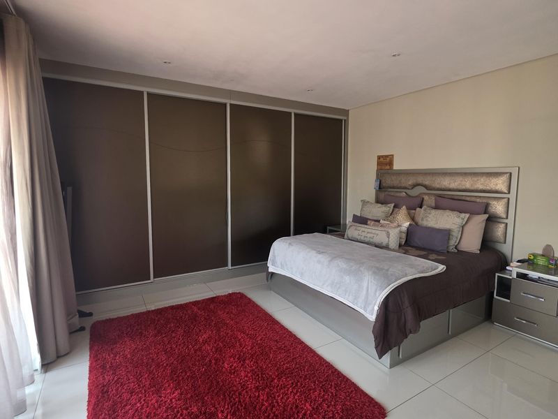 Spacious bedroom featuring large built-in cupboards, modern tiled flooring, and recessed ceiling lighting.