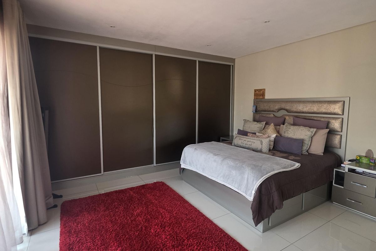 Spacious bedroom featuring large built-in cupboards, modern tiled flooring, and recessed ceiling lighting.