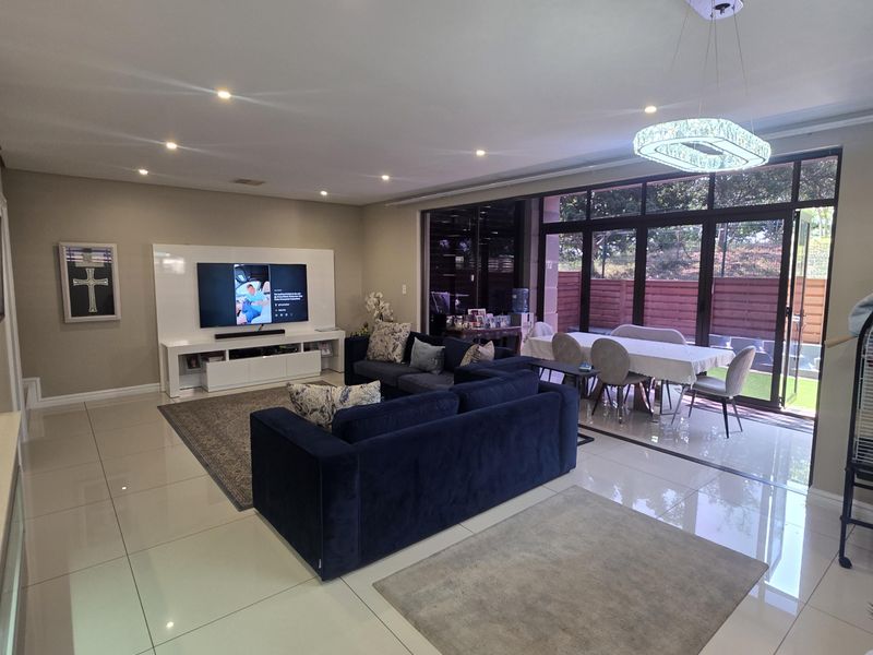 Spacious open-plan living and dining area featuring polished porcelain tiles, recessed lighting, and large sliding glass doors leading to the outdoor space.