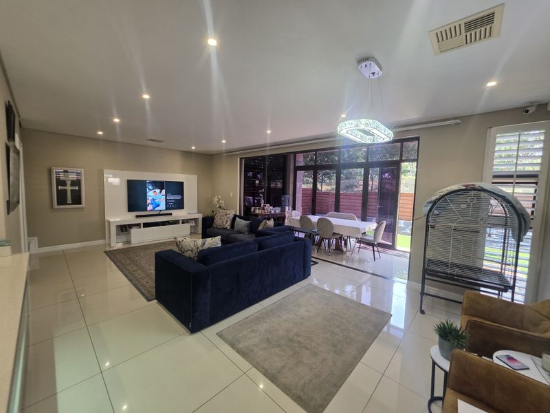 Spacious open-plan living and dining area featuring polished porcelain tiles, recessed lighting, and large sliding glass doors providing seamless access to the outdoor space.