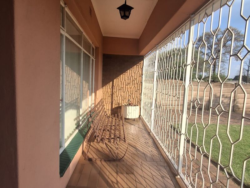 A covered patio area featuring tiled flooring, large windows, and a security gate, offering a functional outdoor space.