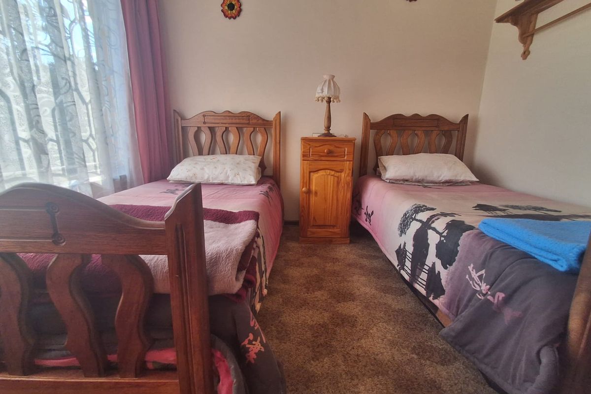 A functional bedroom featuring carpeted flooring and window treatments, offering a comfortable space with potential for modern updates.