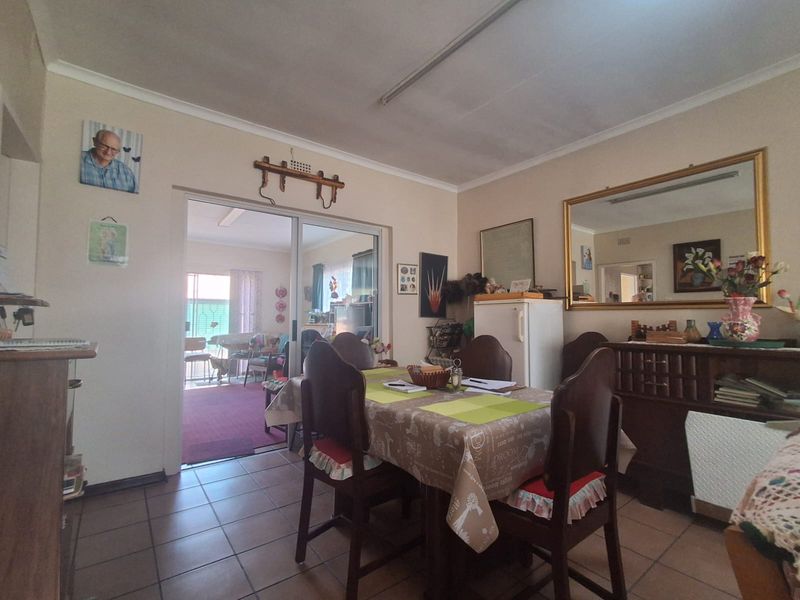 Dining room featuring tiled flooring and a sliding glass door leading to an adjacent living area, with coved ceilings and neutral wall finishes.