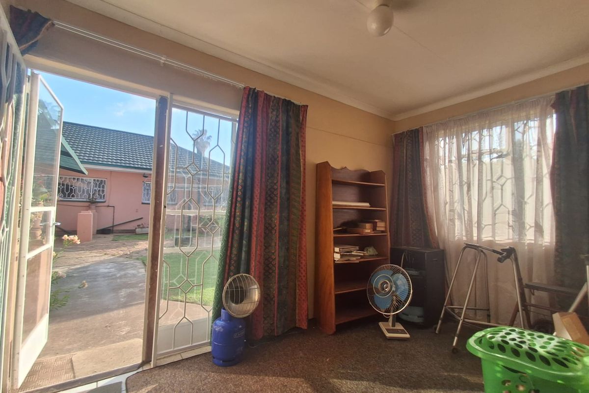 A living room featuring carpet flooring and a sliding glass door with security gate, providing direct access to the rear garden area.