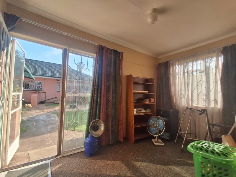 A living room featuring carpet flooring and a sliding glass door with security gate, providing direct access to the rear garden area.