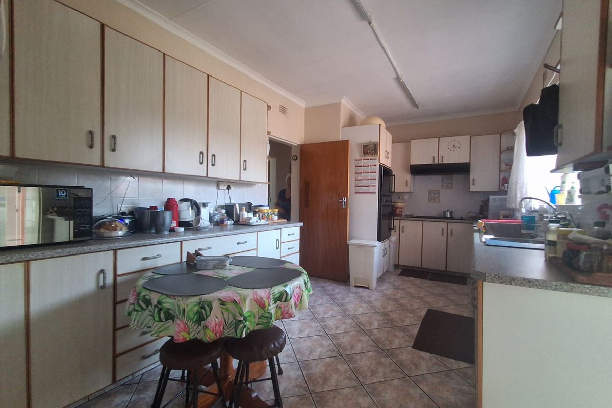 A functional kitchen featuring laminate cabinetry, tiled flooring, built-in oven, and ample counter space, offering a classic layout ready for modern updates.