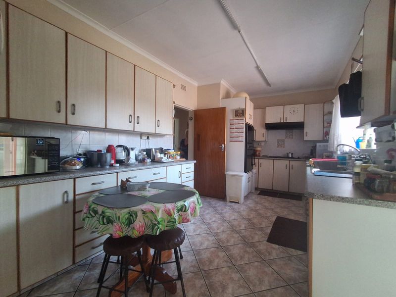 A functional kitchen featuring laminate cabinetry, tiled flooring, built-in oven, and ample counter space, offering a classic layout ready for modern updates.