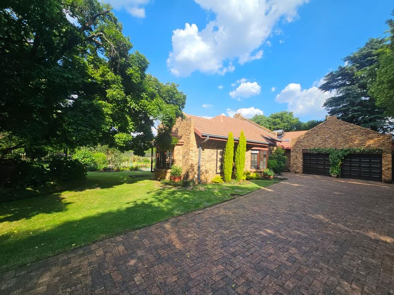A charming face brick house featuring a well-maintained garden, paved driveway, and a double garage, showcasing classic architectural appeal.